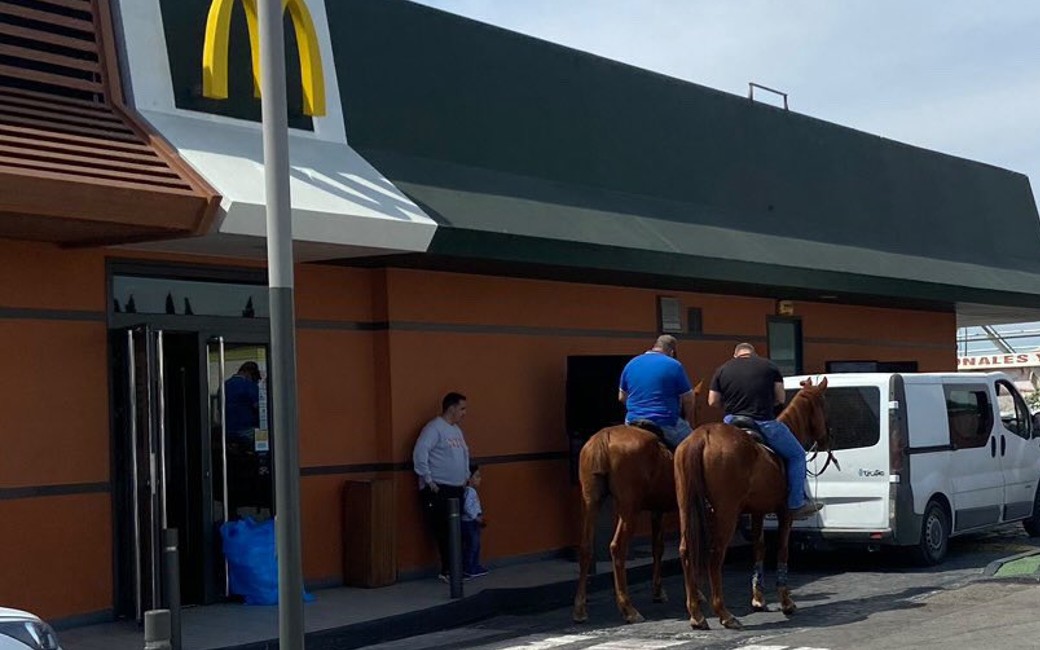 Twee ruiters gaan te paard langs bij de drive-in Mcdonalds in Murcia
