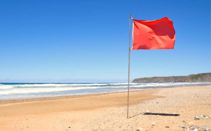 Welke strandvlag waarschuwt voor haaien in Spanje en wat betekenen de gekleurde vlaggen?