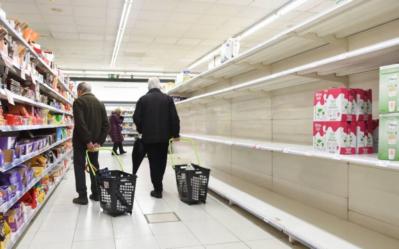 Lege schappen zonnebloemolie, melk, rijst en pasta in Spaanse supermarkten